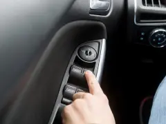 Finger drückt auf Fensterheberschalter. Ein defekter Fensterheber Seilzug reparieren ist oft einfacher als gedacht.