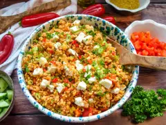 Frischer bulgursalat mit feta, Tomaten, Paprika und Frühlingszwiebeln, garniert mit Petersilie.