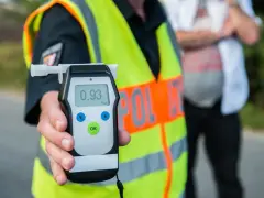 Policjant pokazuje alkomat z wynikiem 0.93 promile alkoholu. Kontrola drogowa trwa.