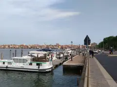 Un vaporetto attracca a Chioggia, con la città sullo sfondo e una strada trafficata.