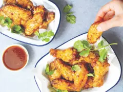 Chrupiące skrzydełka z airfryer, podane z sosem i świeżą kolendrą. Idealna przekąska na imprezę.