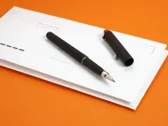 Eleganckie pióro na białej kopercie, gotowe do wypełnienia. Może to być formularz do pełnomocnictwa pocztowego przez internet.