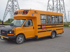 Żółty autobus szkolny GMC z napisem "SHARP" i znakiem STOP. Zastanawiasz się, ile kosztuje autobus?