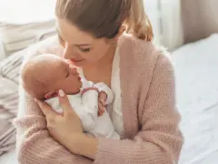 Delikatna pozycja do odbijania noworodka w ramionach mamy, która tuli go z miłością.