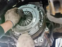 Mechanik w rękawiczkach montuje tarczę sprzęgła, przygotowując wysprzęglik sprzęgła do pracy.