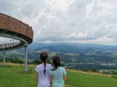Dwie dziewczynki podziwiają malownicze góry sowie z tarasu widokowego.