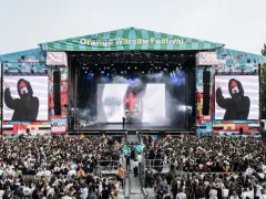 Tłum ludzi na Orange Warsaw Festival 2026, scena z artystą na ekranie i dymem.