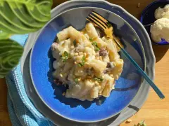 Piatto di pasta con cavolfiore cremoso, guarnito con pinoli e erbe aromatiche. Un primo piatto gustoso e leggero.