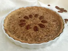Torta di noci croccante e dorata, decorata con noci intere disposte a cerchio. Un delizioso pandi noci pronto da gustare.