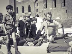 Chłopcy w harcerskich mundurkach i mężczyzna w wojskowym ubraniu przy samochodzie terenowym. Scena jak z polskich seriali dla młodzieży lat 70.