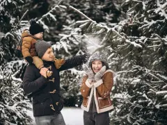 Rodzina cieszy się śnieżną zabawą podczas ferii zimowych 2026 w Podlaskiem. Ojciec niesie synka na barana, a mama śmieje się, gdy sypie śniegiem.