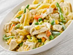 Penne z kurczakiem i warzywami w kremowym sosie. Danie zawiera zieloną fasolkę, groszek, kukurydzę i marchewkę.