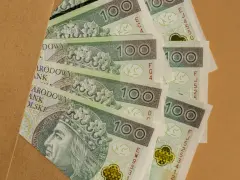 Stos banknotów 100 zł, idealnych na prezent, ile daje się na komunię?
