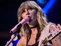 Taylor Swift śpiewa do różowego mikrofonu, grając na gitarze. To scena z jej epickiej trasy "reputation stadium tour", która na zawsze zmieniła jej wizerunek.