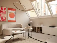 Mansarde da sogno con divano accogliente, tavolini, poster musicali e vista sui tetti.