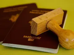 Drewniany stempel nad paszportem, gotowy do pieczętowania. Marzysz o podróży? Biuro paszportowe Lublin pomoże Ci spełnić marzenia.