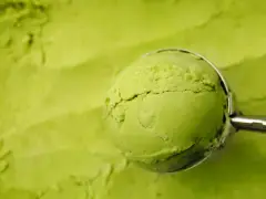 Eine Kugel cremiges Matcha-Eis wird mit einem Löffel aus einer Schüssel gehoben. Perfekt für ein erfrischendes Matcha Eis Rezept.