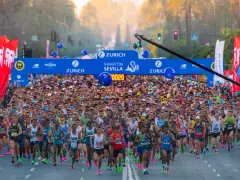 Multitudinaria salida del maratón Sevilla 2026, con miles de corredores bajo el arco de meta.