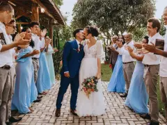 Un couple s'embrasse lors d'un mariage intime, entouré d'invités applaudissant.