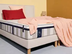 Un matelas rayé, drapé d'une couverture rose pâle, avec des coussins rouge et rose. La question est : combien de ressorts pour un bon matelas ?