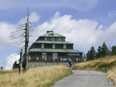 Schronisko Odrodzenie w Karkonoszach, z charakterystyczną architekturą i otoczone suchymi drzewami.