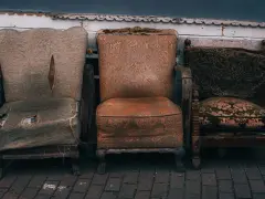 Trzy zniszczone fotele, które wyglądają, jakby czekały na to, gdzie wywieźć stare meble.