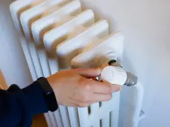 Ajustando el termostato de un radiador para optimizar la calefacción central en comunidades de vecinos.