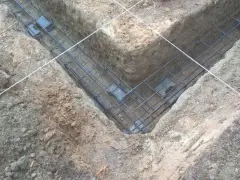 Zbrojenie fundamentów prefabrykowanych w wykopie. Stalowe pręty tworzą siatkę, gotową do zalania betonem.