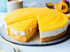 Eine saftige Pfirsich Maracuja Torte mit Biskuitboden, cremiger Füllung und fruchtigem Topping. Ein Stück ist bereits angeschnitten.