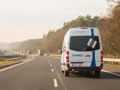 Biały bus AR-SPEED jedzie autostradą. Zastanawiasz się, ile kosztuje bus do Niemiec? Sprawdź na ar-speed.pl.