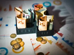 Billets d'euros enroulés dans des porte-billets, pièces et graphiques financiers. Illustration de la rémunération mandataire social.