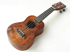 Drewniane ukulele z widocznymi śladami użytkowania. Na gryfie widać progi, a na pudle rezonansowym struny. Idealne do nauki chwytów na ukulele.