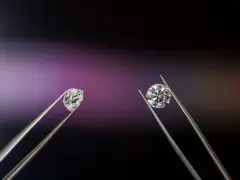 Dwa kamienie szlachetne w pęsecie: surowy brylant i oszlifowany diament.