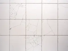 Pęknięte białe płytki tworzą mozaikę. Zastanawiasz się, jak zamaskować pękniętą płytkę?