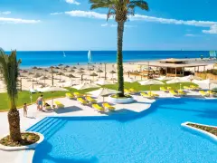Słoneczny dzień na plaży w Tunezji. Basen, palmy i leżaki zapraszają do relaksu.