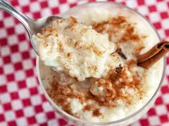 Cuchara con cremoso arroz con leche, espolvoreado con canela. ¿Quién inventó el arroz con leche? ¡Este postre es un clásico!