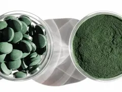 Dwie szklane miseczki: jedna z tabletkami chlorelli, druga z zielonym proszkiem. Dowiedz się, chlorella jak stosować, by czerpać z niej korzyści.