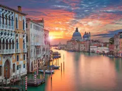 Tramonto sul Canal Grande, un quadro perfetto di posti romantici a Venezia. Palazzi storici e la Basilica di Santa Maria della Salute riflettono i colori del cielo.