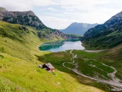 Idyllischer Salzburg See, umgeben von grünen Bergen. Eine Hütte am Hang lädt zum Verweilen ein.