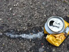 Zgnieciona puszka po piance montażowej leży na asfalcie, obok śladów piany. Pamiętaj o prawidłowej utylizacji!