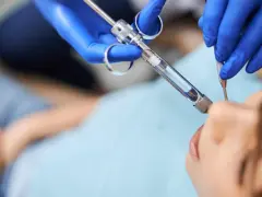 Dentysta podaje znieczulenie miejscowe pacjentowi.