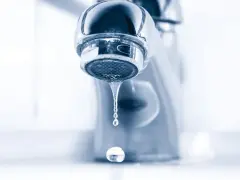 Gouttelettes d'eau tombant d'un robinet de salle de bain qui fuit. Un petit désagrément qui coûte cher.