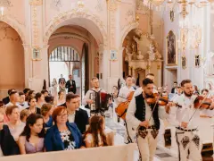Muzycy w strojach ludowych zapewniają oprawę muzyczną ślubu w kościele. Grają na skrzypcach i akordeonie.