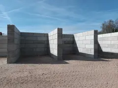 Budowa muru oporowego z betonowych bloczków na piaszczystym podłożu.