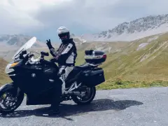Motocyklista w kasku pozdrawia na tle gór. Przełęcz Stelvio zamknięta, ale widoki zapierają dech w piersiach.