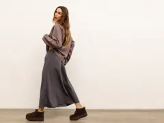 Modelka w luźnej, szarej spódnicy i brązowej bluzce. Idealny zestaw, który pokazuje, co pasuje do szarej bluzki.