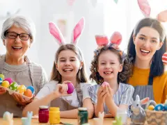 Familie feiert die Osterferien BW 2026 mit bunten Eiern und Hasenohren.