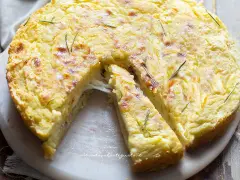 Una fetta di torta di patate filante, dorata e profumata al rosmarino, pronta per essere gustata.
