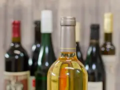 Butelki z winem na tle drewnianej ściany. Zastanawiasz się, ile alkoholu można wziąć do Norwegii samolotem?
