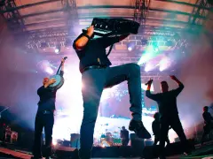 Energetyczne koncerty Dropkick Murphys: muzyk gra na akordeonie, inny na banjo, a w tle wokalista z mikrofonem.